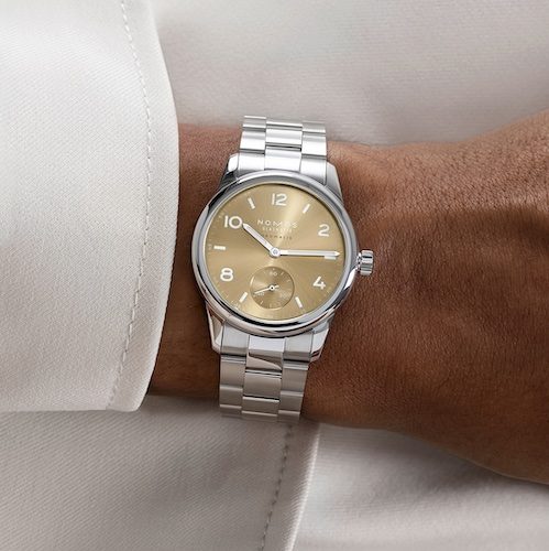 Nomos Glashütte Club Sport Neomatik 34 Gold Handgelenk Das goldfarben galvanisierte Zifferblatt ist mit einem Sonnenschliff versehen.