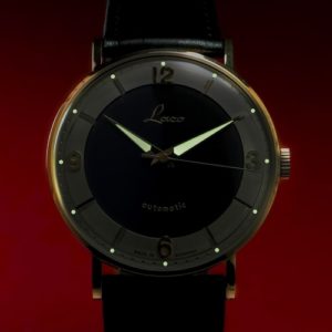 Stunden- und Minutenzeiger und die Indexpunkte sind im Dunkeln ablesbar.