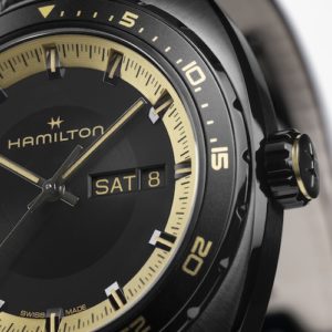 Die Zeiger und Ziffern sind goldfarben gestaltet, ebenso der äußere Ring und die Krone.