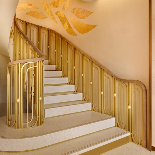 Eine goldfarbene, geschwungene Treppe führt in das Zwischengeschoss.